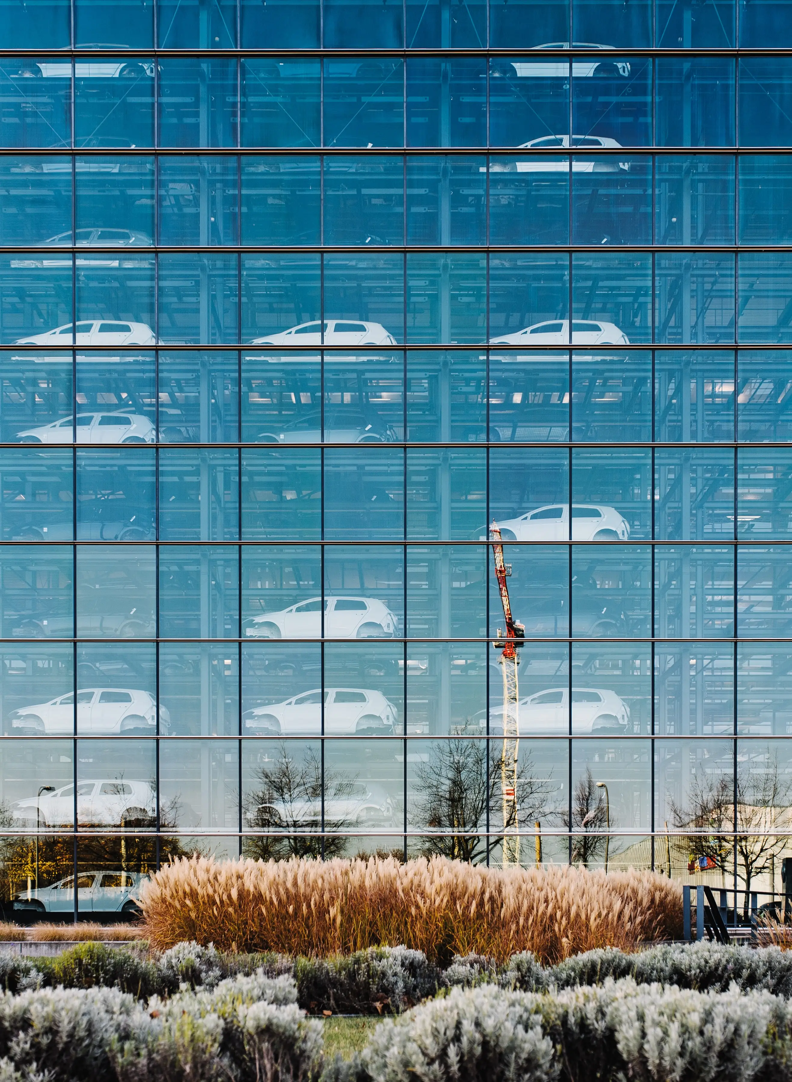 Finished vehicles stacked behind the glass facade of an automotive storage tower